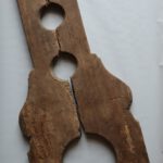 zweiteilige Schandgeige aus Holz, die von der Form her an das gleichnamige Musikinstrument erinnert, mit einer großen Aussparung für den Kopf und zwei kleinen für die Hände, als Objekt im Strafvollzugsmuseum ausgestellt