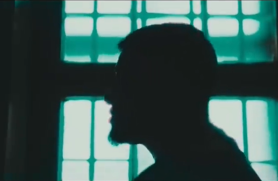 Silhouette des Künstlers Eska, die sich dunkel vor dem Hintergrund eines mit Gitterstäben versehenen Fensters abzeichnet