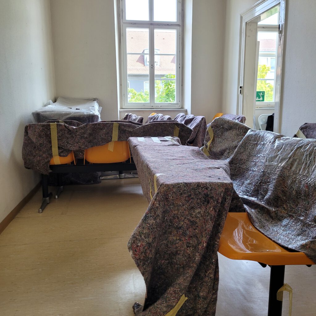 Raum im Obergeschoss des Strafvollzugsmuseums, der während des Umbaus mit den gelben Stühlen aus dem RAF Gerichtsaal vollgestellt ist