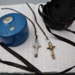 Blaues, hohes Uhrengehäuse, sogenannte Wächterkontrolluhr, die neben einem passenden Tragekoffer aus Leder und zwei Stockwerkschlüsseln auf einem Kontrollbuch liegt