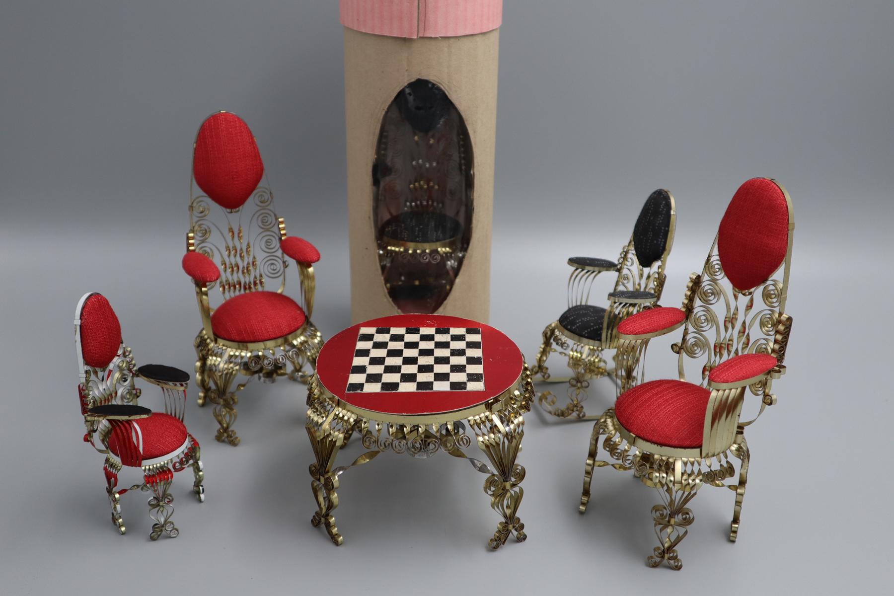 Puppenmöbel-Set bestehend aus zwei großen Stühlen und einem kleinen Stuhl mit roter Polsterung, einem Schaukelstuhl mit grauer Polsterung und einem Tisch mit roter Oberfläche und einem aufgemalten Schachbrett, hergestellt aus Blechdosen, Objekt im Strafvollzugsmuseum