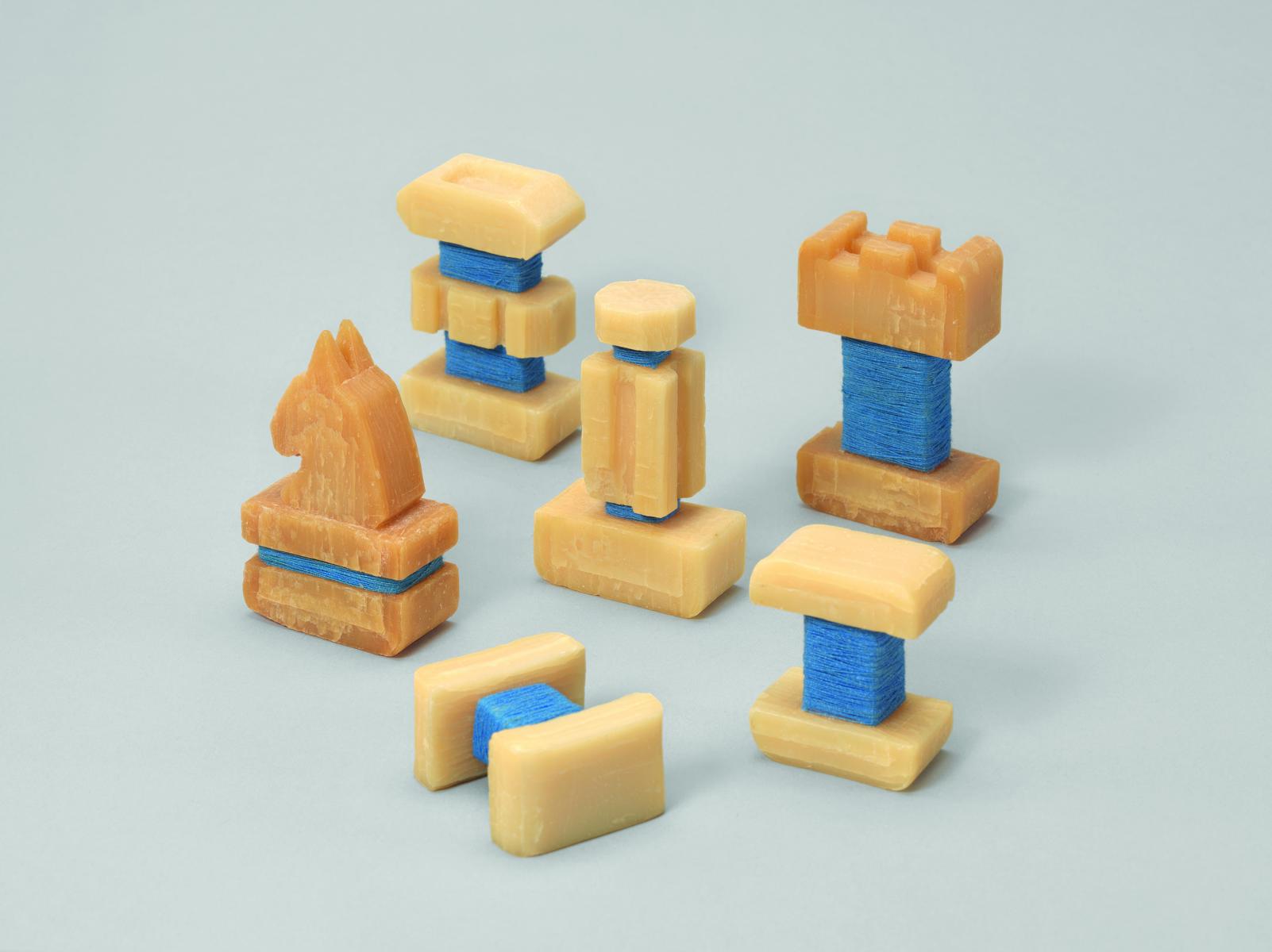 Schachfiguren aus beiger Kernseife geschnitzt und mit blauer Schnur umwickelt