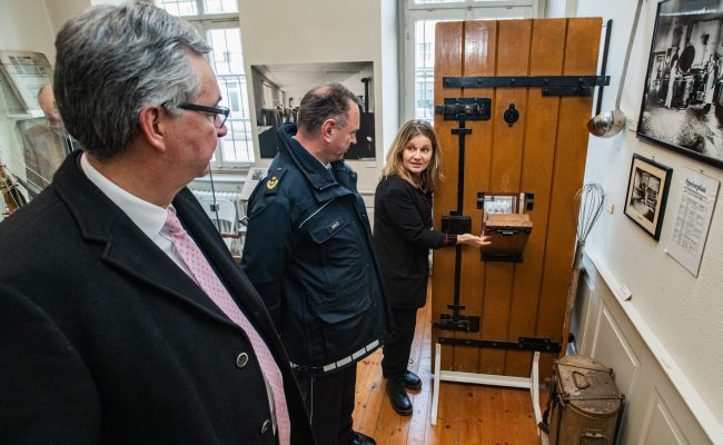 Museumsleiterin Opfermann führt Landrat Allgaier und Polizeipräsident durch die Dauerausstellung des Strafvollzugsmuseum.
