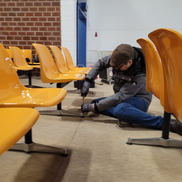 Mitglied des Fördervereins des Strafvollzugsmuseums baut die gelben Stuhlreihen aus dem RAF Gerichtssaal in Stuttgart-Stammheim aus